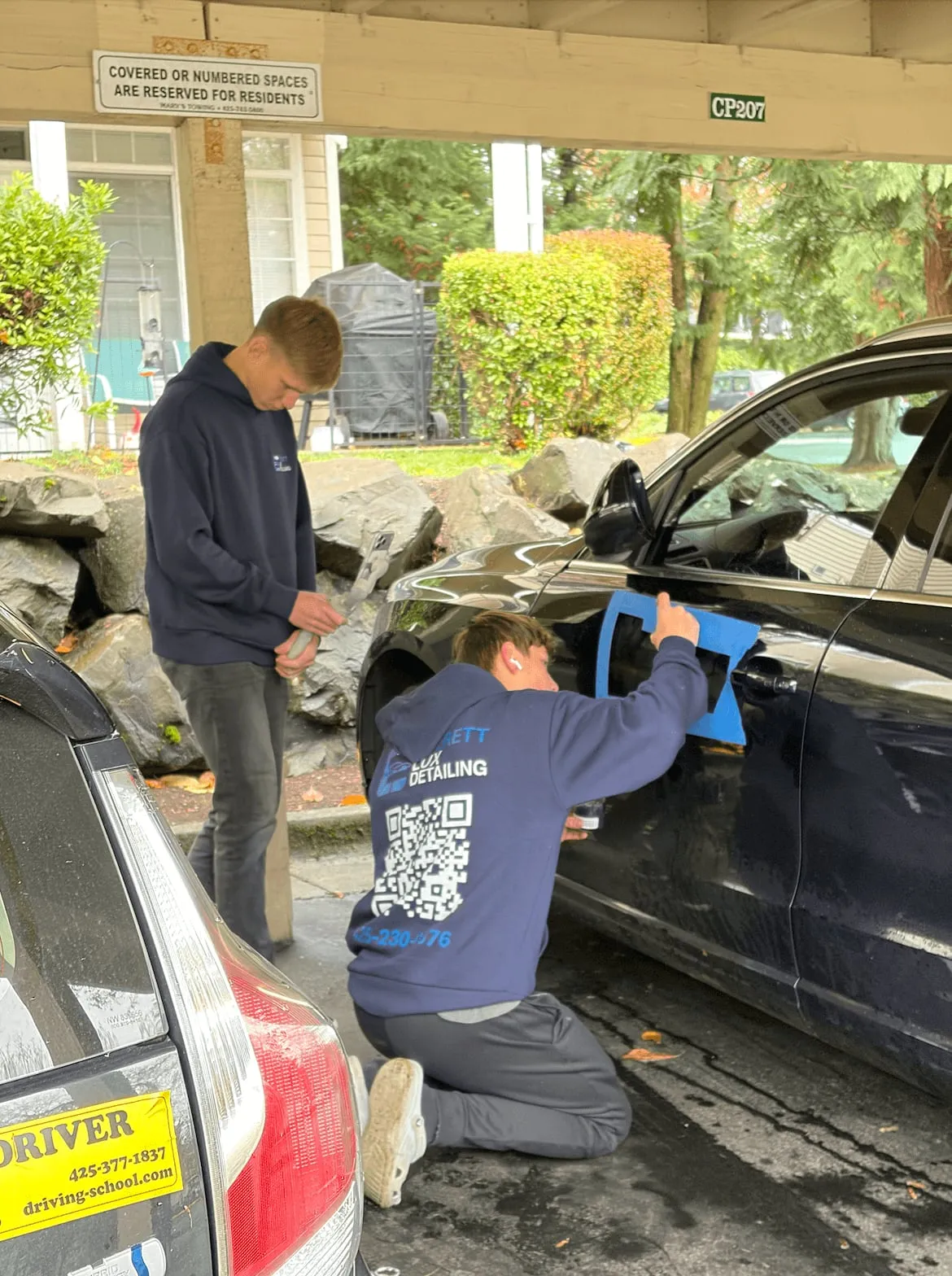 Everett Lux Detailing detailers working on a car in an apartment carport