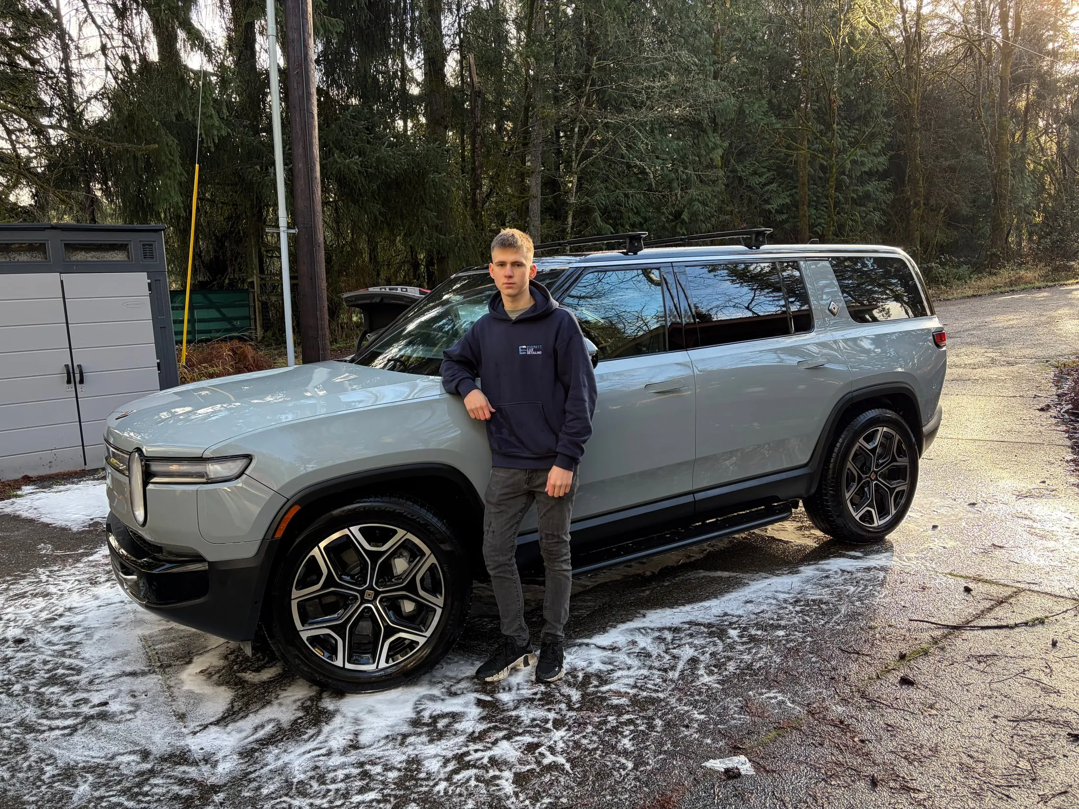Detailer beside a Rivian SUV after a mobile wash