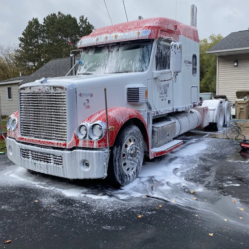 Semi truck cab covered in wash foam during a fleet detail