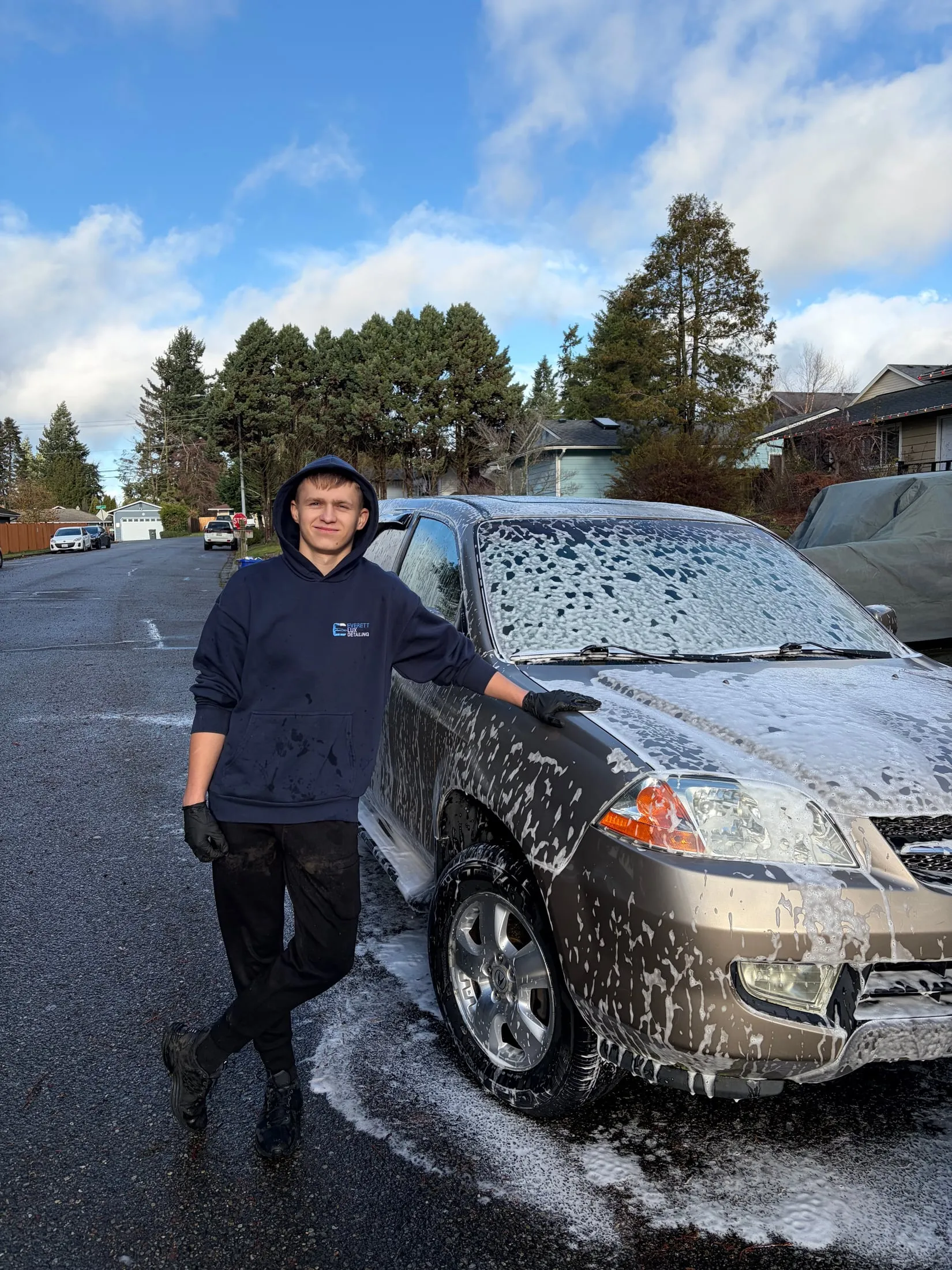 Detailer next to an SUV covered in wash foam